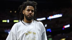 J. Cole walking at a basketball game.
